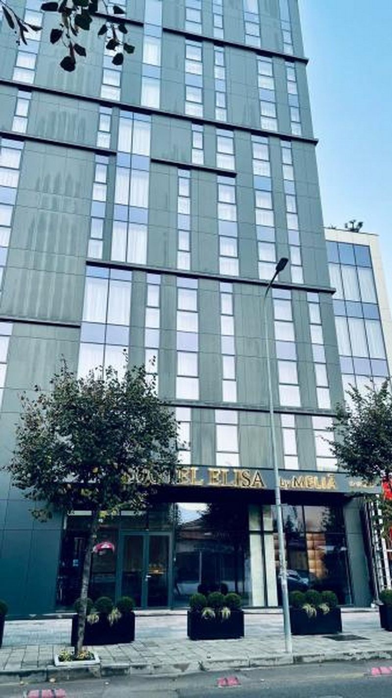 A modern building with a glass facade and a sign reading "Hotel Elisa."