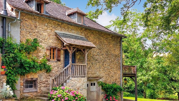 Ein Steinhaus mit einer Holztreppe, einer Holztür und einer kleinen Veranda.