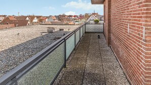 A rooftop terrace with a gravel floor, metal railing, and a brick wall. - 1 bedroom amazing apartment in Büsum (Büsum)