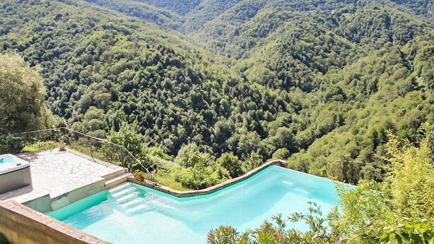 Ein Schwimmbad mit Blick auf ein bewaldetes Tal.