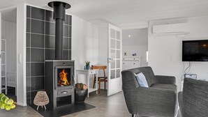 A modern living room with a fireplace, grey sofas, a television, and a white cabinet.