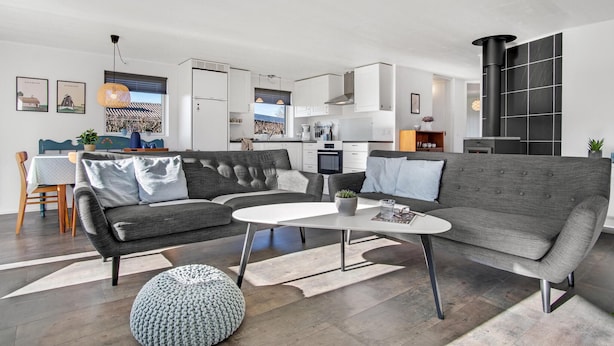 A modern living room with a grey sofa, a coffee table, and a knitted pouf.