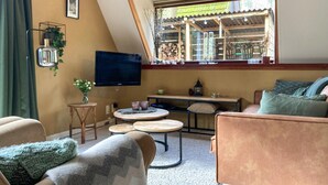 Una sala de estar acogedora con un televisor, una mesita y un sofá.