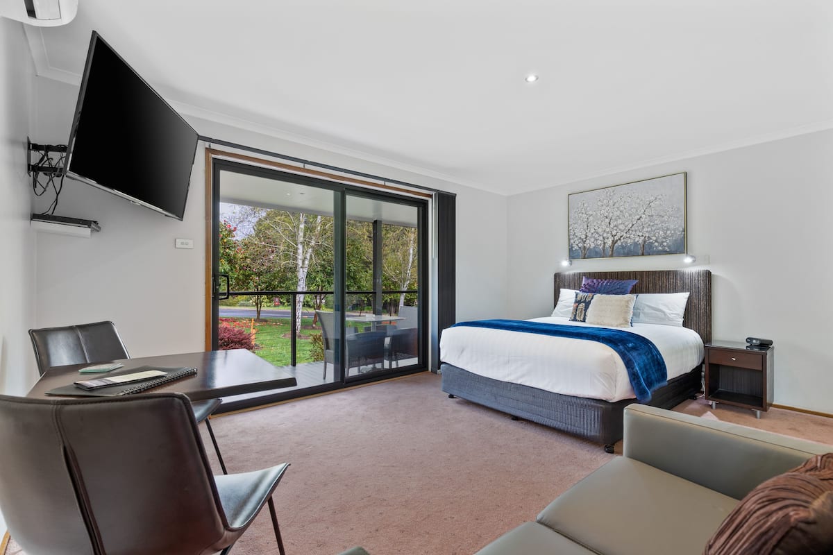 A modern bedroom with a bed, a desk, and a TV.