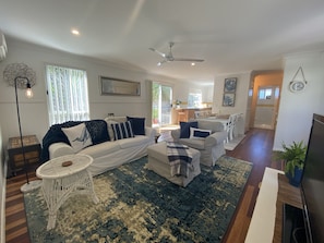 Relax in this spacious living area with a comfortable sofa set, dining table, and mounted TV.