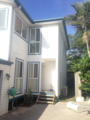 Stylish two-story home with a charming entrance, complete with a small staircase and a welcoming potted plant.