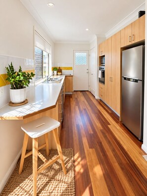 Une cuisine moderne avec des meubles en bois, un réfrigérateur en acier inoxydable et une plante en pot.