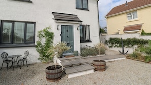 Et toetagers hus med hvide facader, en hoveddør og en lille terrasse med et bord og stole.