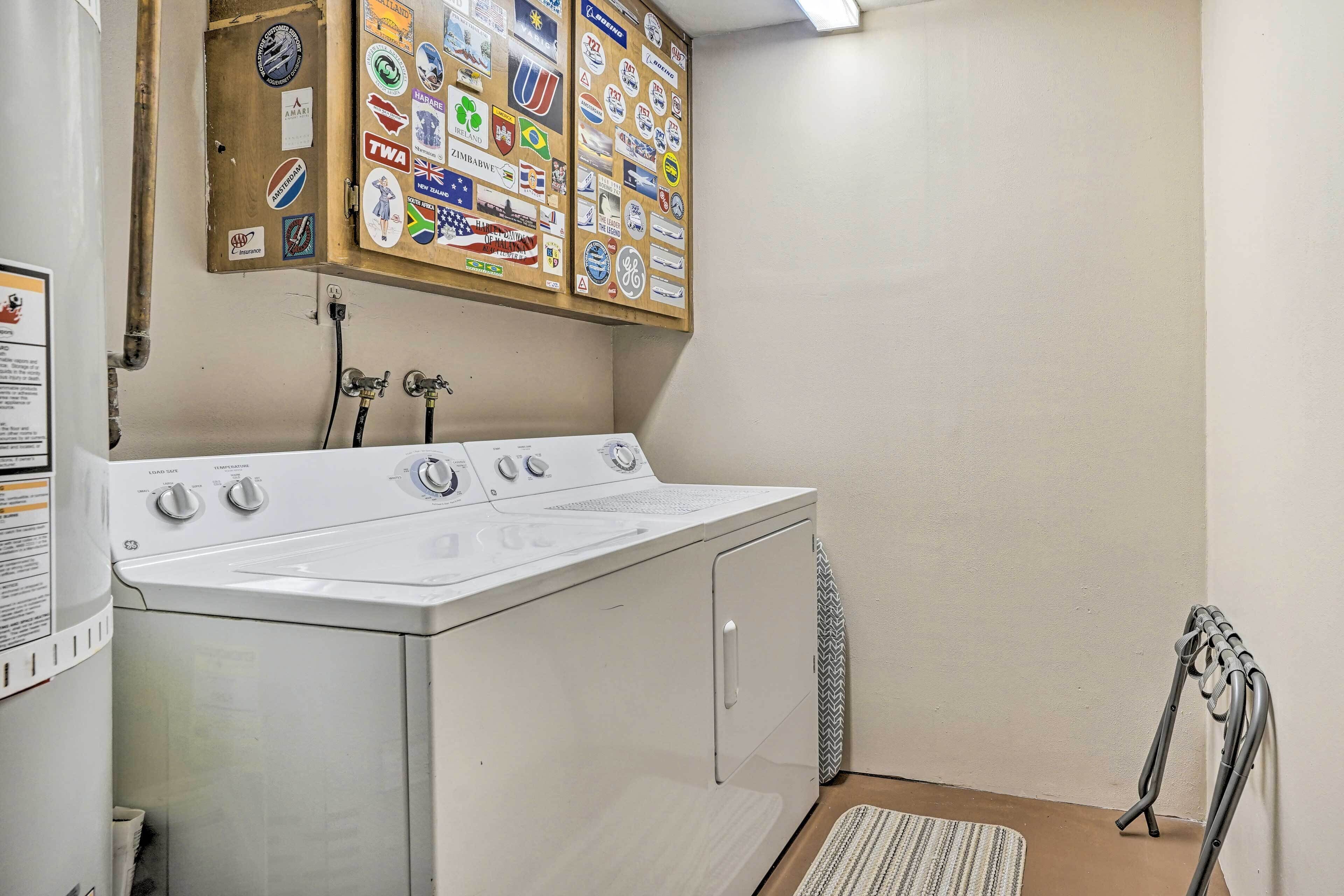 Une buanderie équipée d’un lave-linge et d’un sèche-linge à chargement frontal, d’un tableau d’affichage orné de divers autocollants et d’un radiateur.