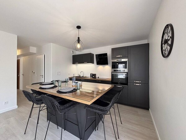 A modern kitchen with dark cabinetry, a central island with bar stools, and built-in appliances.