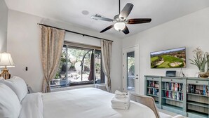 A bedroom with a large bed, a ceiling fan, a TV, and a bookshelf. - Scottsdale Grayhawk entire house with Private Pool, Sunroom, Office (Scottsdale)