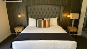 Ein großes Bett mit einer gepolsterten Kopfteile, zwei Nachttische und eine Lampe auf jeder Seite.