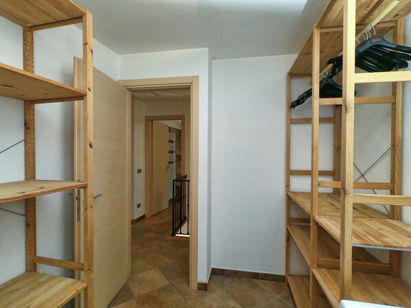 Un pasillo estrecho con estanterías de madera a ambos lados, que conduce a una habitación con suelo de baldosas.