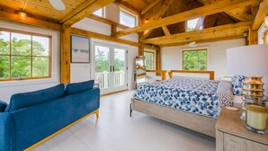 Une chambre spacieuse avec un grand lit, un canapé bleu et un plafond en bois.
