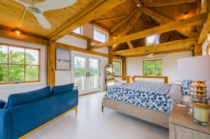 Une chambre spacieuse avec un grand lit, un canapé bleu et un plafond en bois.
