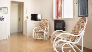 Un salon avec deux fauteuils à bascule, un téléviseur et une cheminée.