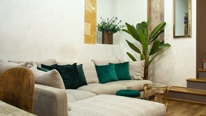 A living room with a sectional sofa, a large green plant, and a small side table.