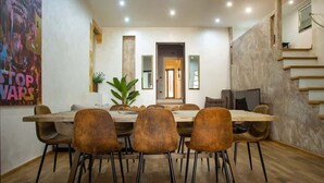A dining area with a long wooden table, six brown chairs, and a potted plant.