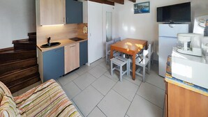 Eine kompakte Küche mit Essbereich, einer Holztreppe und einem an der Wand montierten Fernseher.