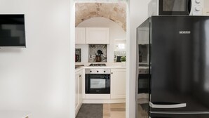 Eine kleine Küche mit weißen Schränken, einem schwarzen Kühlschrank und einer Mikrowelle.
