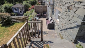 Ein Steinhaus mit einer Holzdielen-Terrasse und Sitzgelegenheiten im Freien.