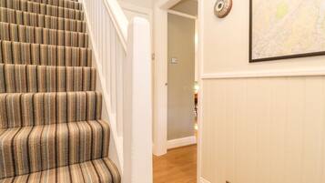 A staircase with striped carpet, a wall-mounted map, and a door leading to another room.