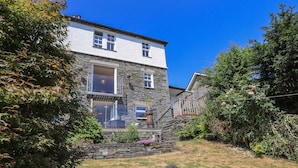 Ein zweistöckiges Steinhaus mit einer Steintreppe, die zu einem Balkon führt.