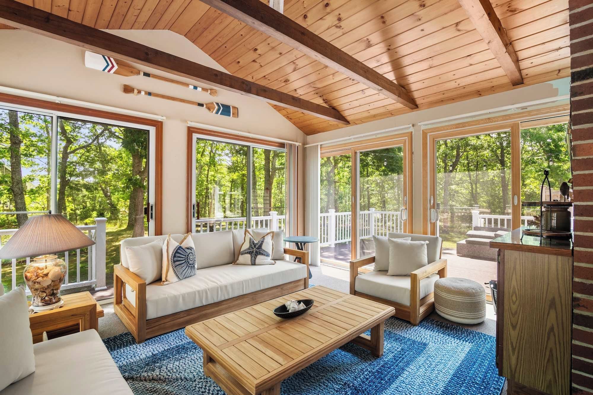 A spacious living area with a wooden ceiling, large windows, and a view of the outdoors.
