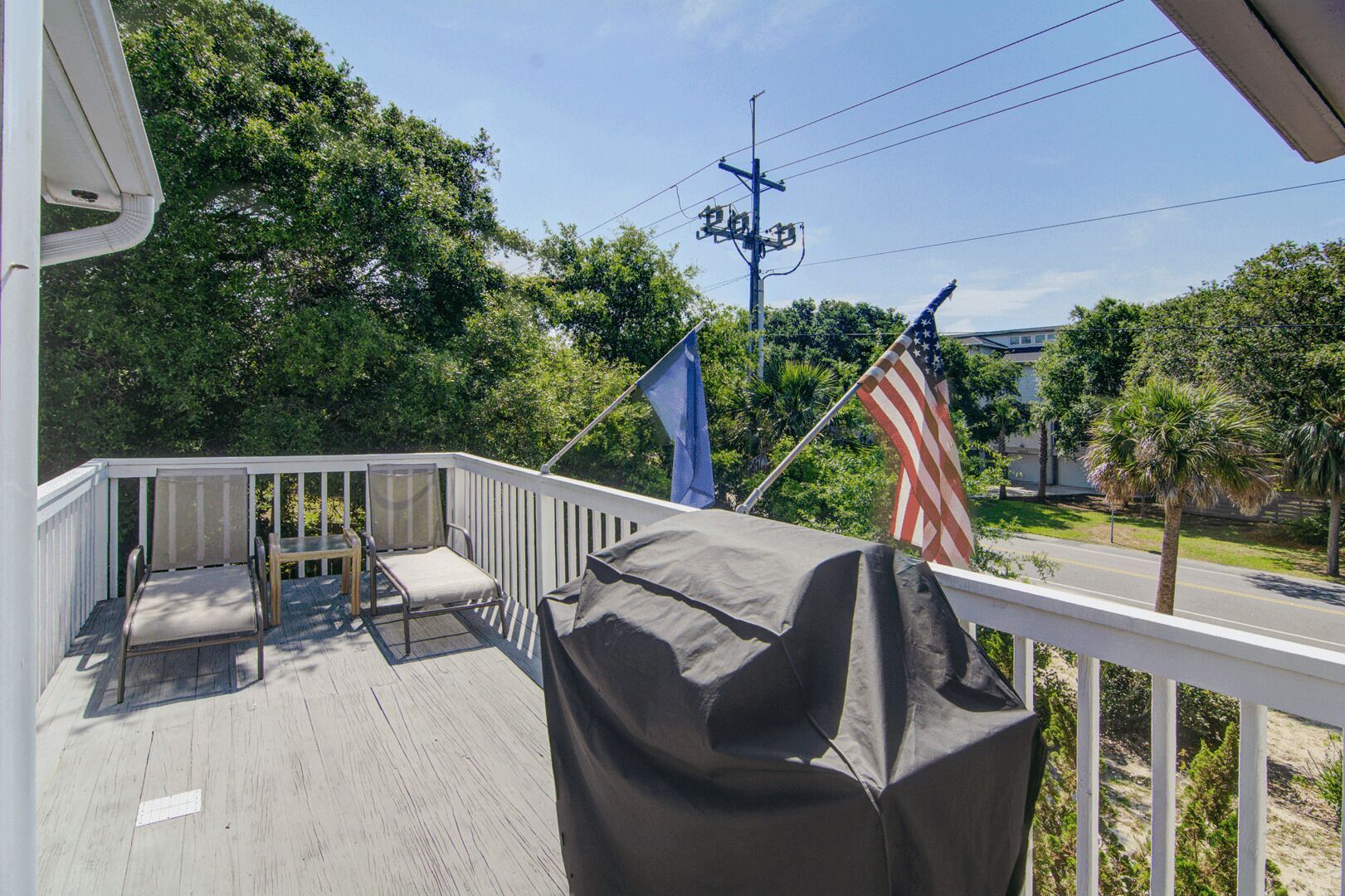A wooden deck with outdoor furniture, an American flag, and a blue flag.
