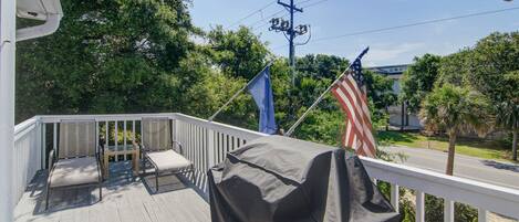 A wooden deck with outdoor furniture, an American flag, and a blue flag.