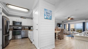 Una cocina moderna con armarios blancos, electrodomésticos de acero inoxidable y un adorno azul con motivos marinos.