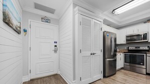 Una cocina con armarios blancos, un refrigerador de acero inoxidable, un microondas y un horno.