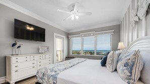 Un dormitorio con cama, cómoda, televisor y vista al océano.