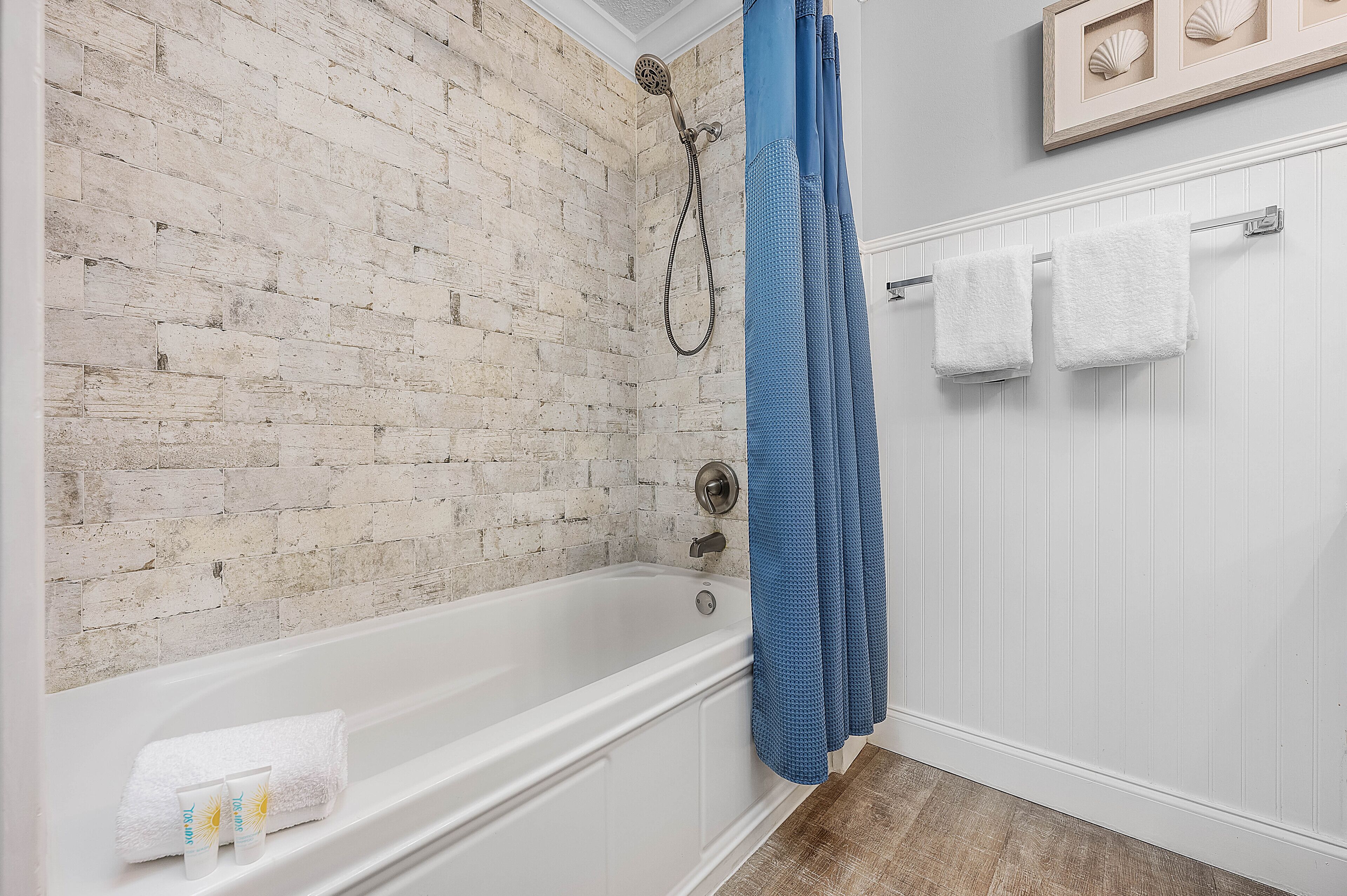 Een badkamer met een witte badkuip, een blauw douchegordijn en een witte handdoekhouder.