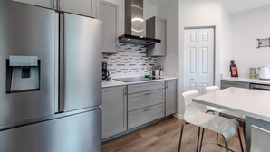 A modern kitchen with stainless steel appliances, a white countertop, and a tiled backsplash. - Welcome at Coastal Soul perfect place for traveling Family  (Vero Beach)