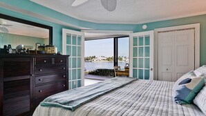 A bedroom with a bed, a dresser, and a view of a body of water.