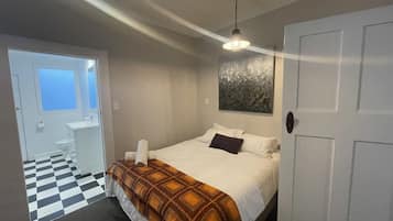 Un dormitorio con cama, ventana, baño y piso a cuadros.