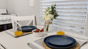 Mesa posta com pratos, copos e um vaso de flores.