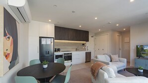 A modern apartment with a dining area, kitchen, living room, and a TV.
