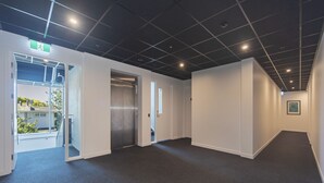 A modern hallway with a dark floor, white walls, and a ceiling with recessed lighting.