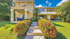 A two-story house with a balcony, a paved pathway, and a well-maintained garden. - Villa el Encanto//Amazing views, walk to beach! (Rincon)
