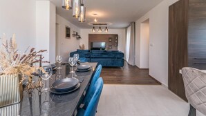 A modern dining area with a long table, chairs, and hanging pendant lights. - Pet friendly home in Tinj (Tinj)