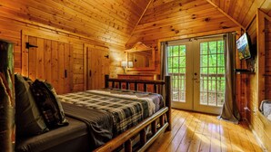 Une chambre dans une cabane en bois, avec un lit, une commode, un miroir et un téléviseur.