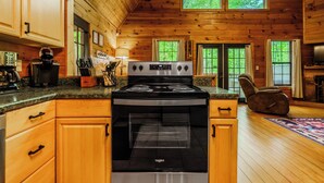 Une cuisine avec des meubles en bois, un fourneau et une vue sur l’extérieur par les fenêtres.