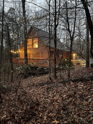 Situated in a forested area, this cabin features a charming front porch with a railing.