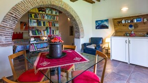 A cozy dining area with a glass table, red cushions, and a bookshelf filled with books. - Cosy apartment in villa with WIFI, A/C, pool, TV, patio, pets allowed and panoramic view (Bucine)