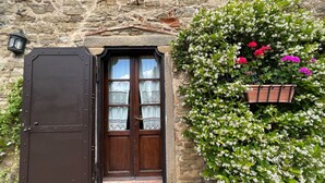 A stone building with a wooden door and a flower box with pink and white flowers. - Beautiful private villa with private pool, hot tub, A/C, WIFI, TV, panoramic view, close to Cortona (Sant'angiolo)