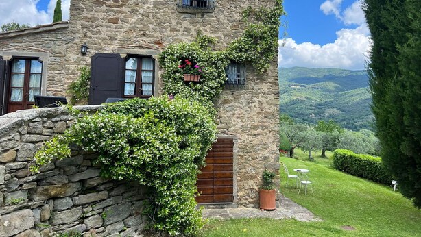 A stone building with a wooden door, a window with a flower box, and a view of green hills. - Beautiful private villa with private pool, hot tub, A/C, WIFI, TV, panoramic view, close to Cortona (Sant'angiolo)