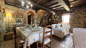 A rustic dining area with a stone wall, wooden ceiling beams, and a chandelier. - Beautiful private villa with private pool, hot tub, A/C, WIFI, TV, panoramic view, close to Cortona (Sant'angiolo)