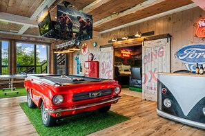 Une table de billard agrémentée d’une maquette de voiture de collection, d’un panneau lumineux au néon et d’un logo Ford d’époque.